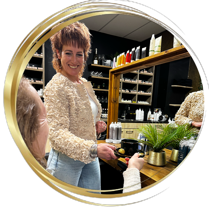 Persoonlijke service in kapsalon: kapster serveert koffie aan klant in een warme en stijlvolle haarsalon.