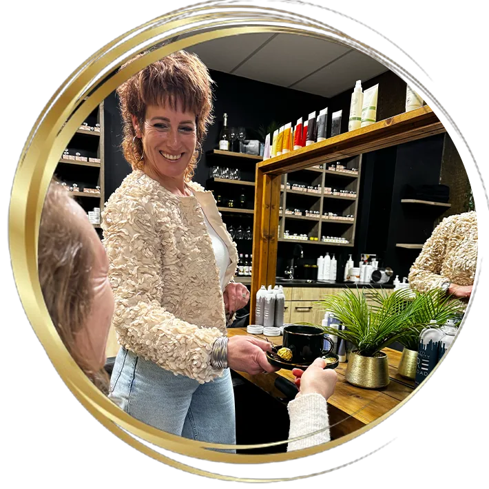 Persoonlijke service in kapsalon: kapster serveert koffie aan klant in een warme en stijlvolle haarsalon.
